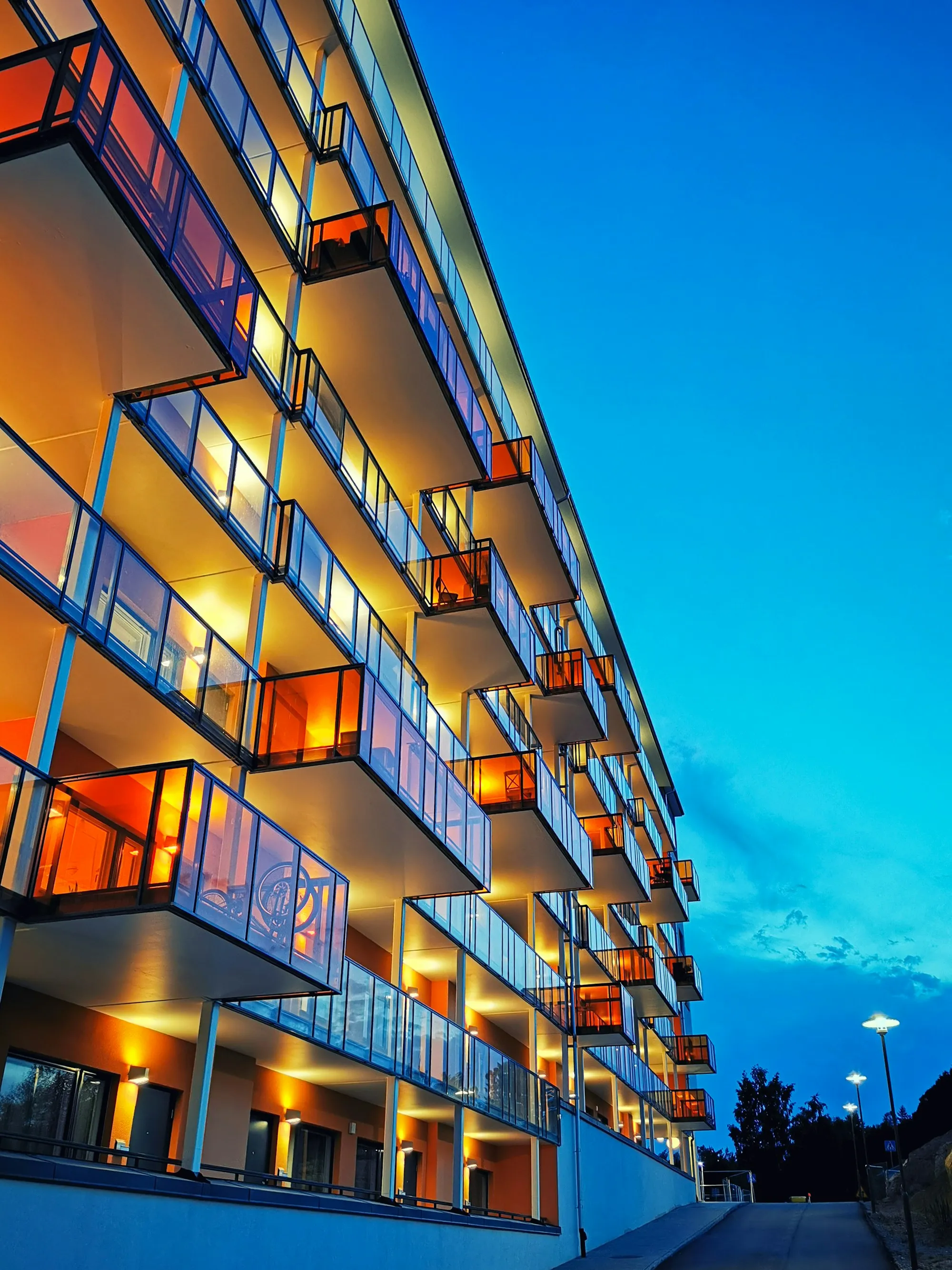 Apartment balconies lit warm against a blue evening sky