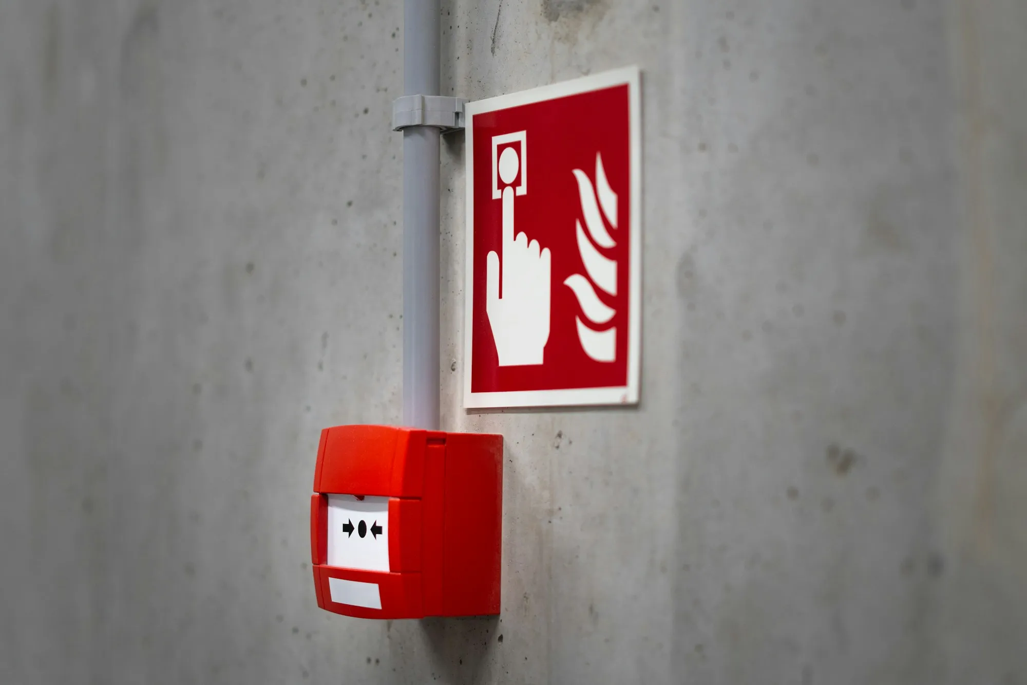 Fire alarm call point and sign on a concrete wall