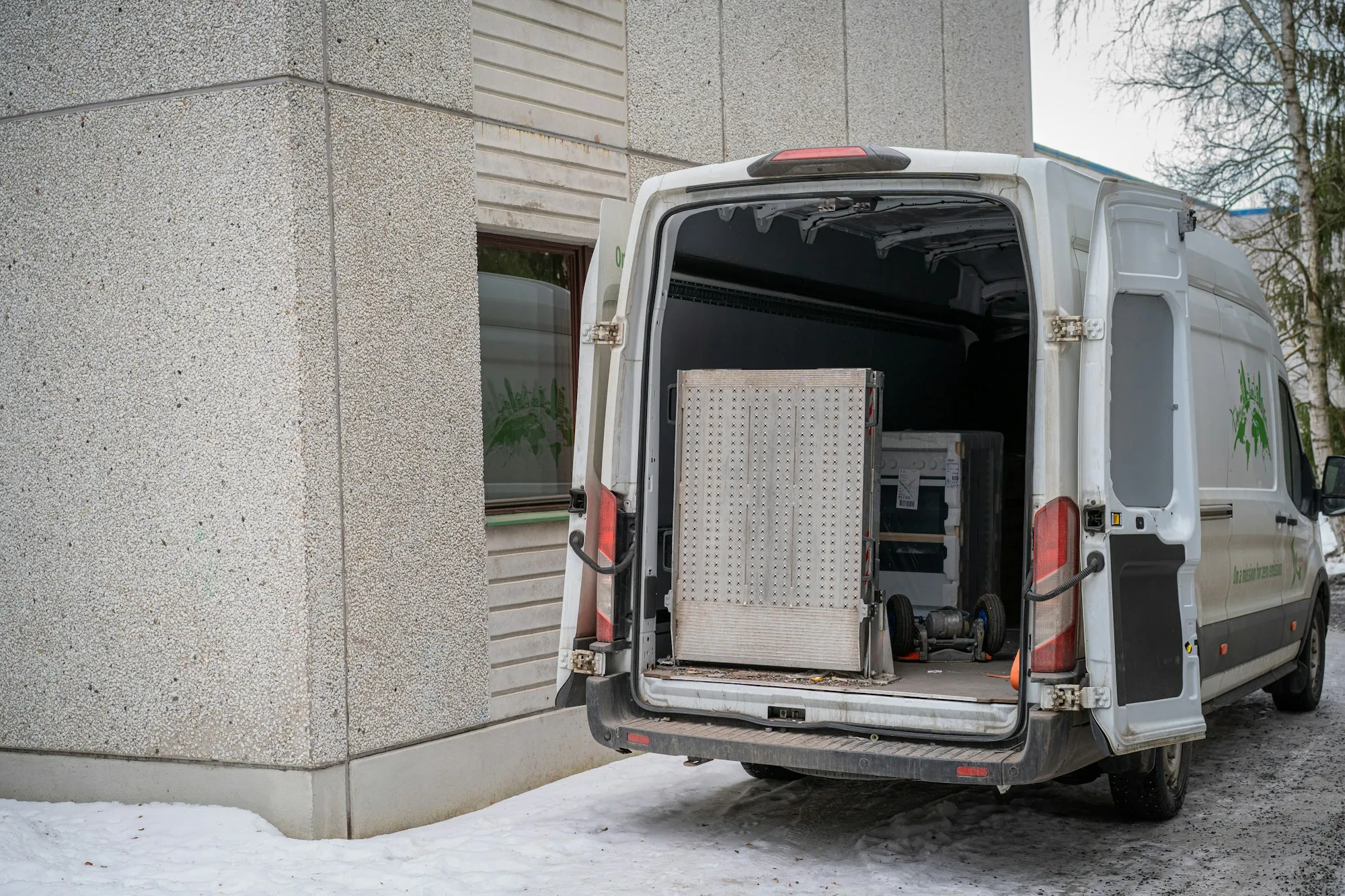 Service van with its rear doors open beside a building entrance