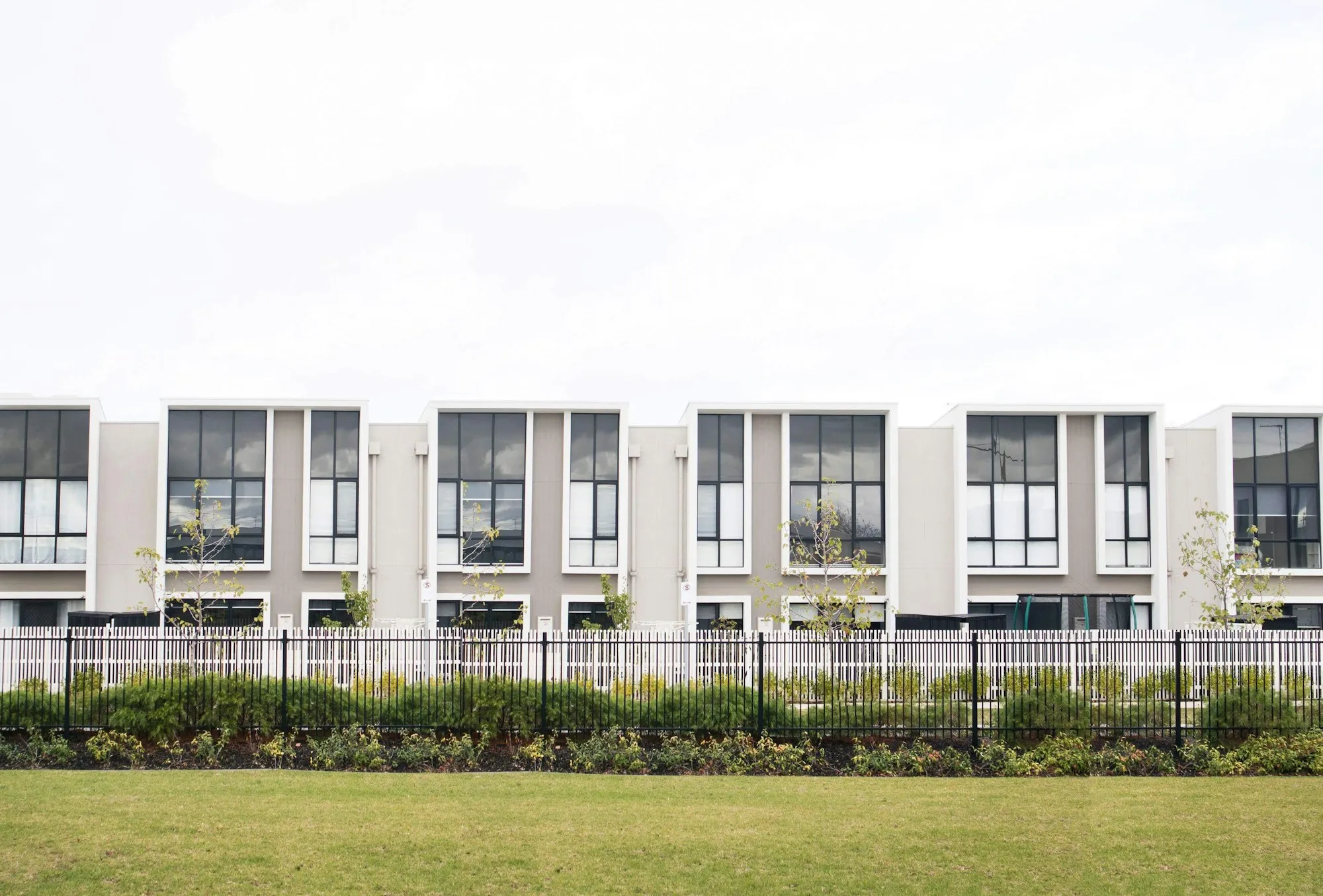 Row of modern managed townhouses behind a lawn